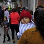 A woman holds a child in a line snaking around the block outside a U.S. immigration office with numerous courtrooms Thursday, Jan. 31, 2019, in San Francisco. The crowd was mixed with people who had court appointments for Thursday, people whose appointments were swallowed up by shutdown and others who had 'Notices to Appear' but assumed that meant they had court dates. (AP Photo/Eric Risberg)