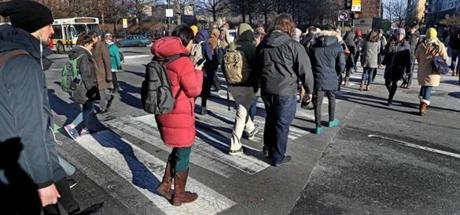 CAMBRIDGE, MA - 1/25/2019: Pedestrians cross Broadway in Cambridge. Cambridge has six subway stops, several major bus lines, and bike lanes everywhere. It?s minutes from downtown Boston, densely packed over just 6.4 square miles, and has enacted several public policies aimed at severely reducing carbon emissions. Yet even Cambridge can?t seem to get its residents to give up their cars ? or, at least, not as quickly as officials would like. (David L Ryan/Globe Staff ) SECTION: METRO TOPIC 
