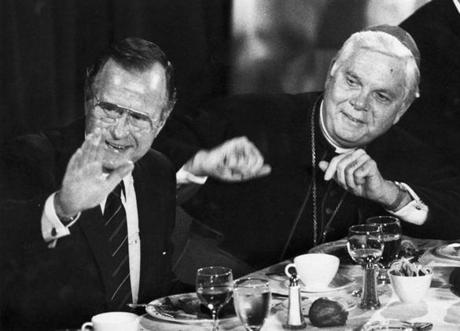 President George H. W. Bush and Cardinal Bernard F. Law sit at a table during a luncheon for the Catholic Lawyers Guild at the Park Plaza Hotel in Boston on Sept. 23, 1989.  
