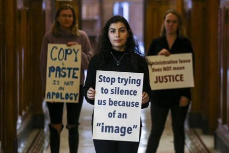 From left, Carson Harold, Mithra Salmassi, and Caroline O?Connor displayed signs they held during a sit-in they helped stage at the College of the Holy Cross in Worcester. 
