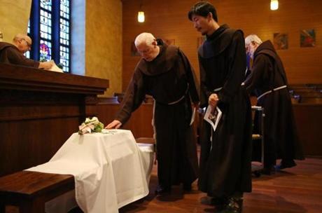 Franciscan Friars pause over over the baby's casket.
