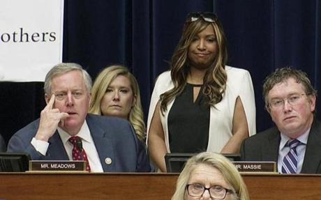 In this image made from a Wednesday, Feb. 27, 2019, video, Rep. Mark Meadows, R-N.C., listens as he questions Michael Cohen, President Donald Trump's former lawyer, as Cohen testifies before the House Oversight and Reform Committee on Capitol Hill in Washington. Lynne Patton, who works in the Trump administration at the Department of Housing and Urban Development, stands behind Meadows, as Meadows said to Cohen, 