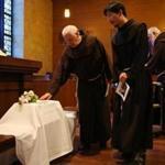 Franciscan Friars pause over over the baby's casket.