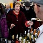 Suzanne Wonson (center) held out her glass to taste a white wine at the Whistlestop Market in Rockport.