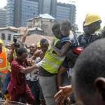 TOPSHOT - Emergency personnel rescue a child at the site of a building which collapsed in Lagos on March 13, 2019. - At least 10 children were among scores of people missing on March 13, 2019 after a four-storey building collapsed in Lagos, with rescuers trying to reach them through the roof of the damaged structure. The children were attending a nursery and primary school on the top floor of the residential building when the structure collapsed. Police said they believed scores of people were trapped under the rubble. (Photo by SEGUN OGUNFEYITIMI / AFP)SEGUN OGUNFEYITIMI/AFP/Getty Images