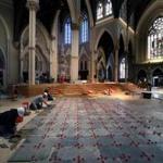 As part of the renovation of the Cathedral of the Holy Cross in Boston, workmen are installing the new marble floors, original pews, exterior lighting, and video and audio technologies.