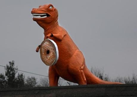 The big orange dinosaur in Saugus is now holding a giant replica doughnut ? an advertisement for a nearby shop. 
