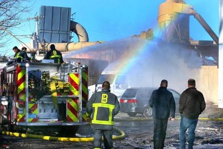A rainbow was present as firefighters poured water on the remains of the New England Casket Co. facility.

