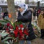 Women representing Utrecht's Muslim community lay a wreath at a makeshift memorial for the victims of a shooting incident in a tram in Utrecht, Netherlands, Tuesday, March 19, 2019. A gunman killed three people and wounded others on a tram in the central Dutch city of Utrecht Monday March 18, 2019. (AP Photo/Peter Dejong)