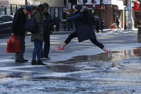 Boston, MA, 03/24/2019 -- A pedestrian leaps over water as she tries to cross Harrison Ave at Kneeland Street after a water main break. (Jessica Rinaldi/Globe Staff) Topic: Reporter: 
