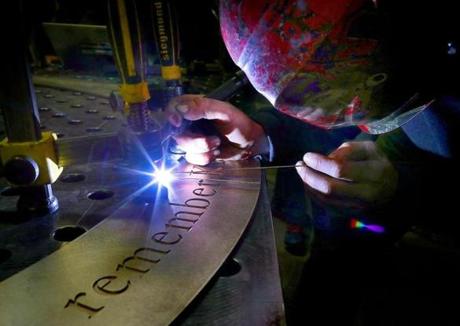 Welder John Mayer works on a seam of a large bronze cirlcle plate that will be on the sidewalk near the finish line and encircle the granite monument to Krystle Campbell.
