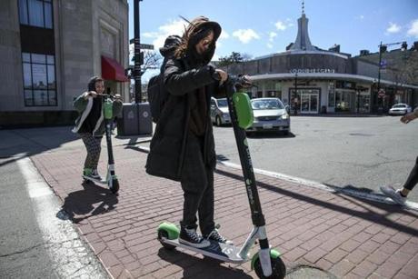 Brookline, MA--04/01/2019--Rayi Ruan (center) rides a Lime scooter across Beacon St. in Brookline on Monday afternoon. (Nathan Klima for The Boston Globe) Topic: 01scooters Reporter:
