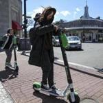 Brookline, MA--04/01/2019--Rayi Ruan (center) rides a Lime scooter across Beacon St. in Brookline on Monday afternoon. (Nathan Klima for The Boston Globe) Topic: 01scooters Reporter: