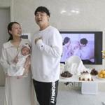 In this April 9, 2019, photo, Lee Dong Kil speaks with his wife Ryu Da Gyeong and daughter Lee Yoon Seol as they celebrate daughter Lee's the 100th day of the birth at their house in Daejeon, South Korea. Just two hours after Lee?s daughter was born on New Year?s Eve, the clock struck midnight, 2019 was ushered in, and the infant became 2-years-old. She wasn?t alone, though it happened for her quicker than most: Every baby born in South Korea last year became 2 on Jan. 1.(AP Photo/Ahn Young-joon)