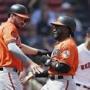Baltimore Orioles' Dwight Smith Jr., left, and Trey Mancini, center, celebrate after scoring on single by Chris Davis off Boston Red Sox's Rick Porcello, right, during the first inning of a baseball game in Boston, Saturday, April 13, 2019. (AP Photo/Michael Dwyer)