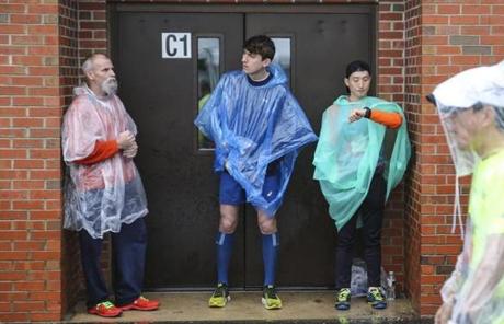 MARATHON SLIDER Hopkinton, MA--04/15/2019--Runners take shelter from the rain under the alcove of a building within Athletes Village before the start of the 123rd annual Boston Marathon on Monday morning. (Nathan Klima for The Boston Globe) Topic: 16marathonphotos Reporter:
