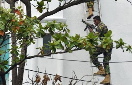 A Sri Lankan Special Task Force personnel climbed a ladder outside a house during a raid on a house in Colombo, Sri Lanka, after a suicide blast killed police searching the property.
