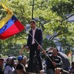 Venezuela's opposition leader and self-proclaimed President Juan Guaido stands above supporters as he addresses them outside La Carlota military air base in Caracas, Venezuela, Tuesday, April 30, 2019. Guaidó has taken to the streets with activist Leopoldo Lopez and a small contingent of heavily armed troops early Tuesday in a bold and risky call for the military to rise up and oust socialist leader Nicolas Maduro. (AP Photo/Fernando Llano)